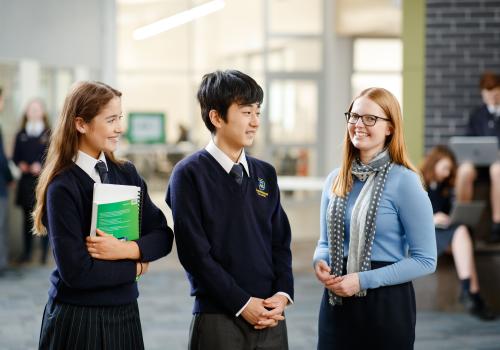 Female teacher standing with high school students