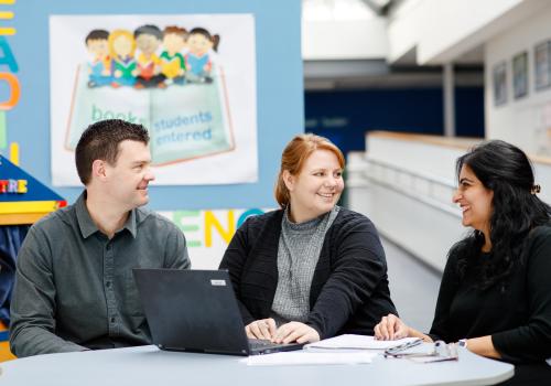 Teachers discussion around laptop