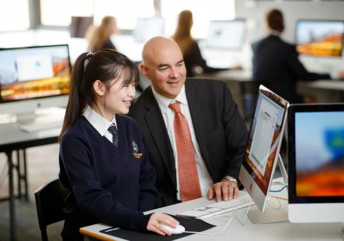 Male teacher with high school students at computer