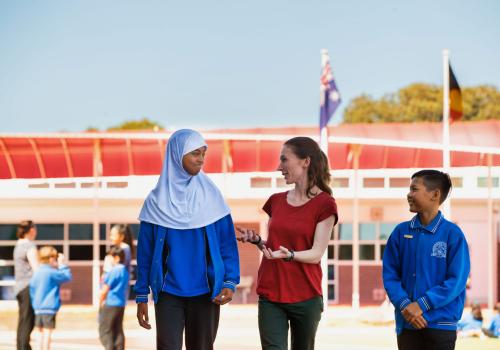 Teacher speaking with primary students outside