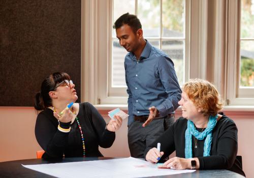 Three adults collaborating around a table. 