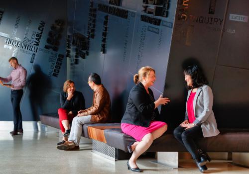 Adults sitting indoors talking in small groups. 