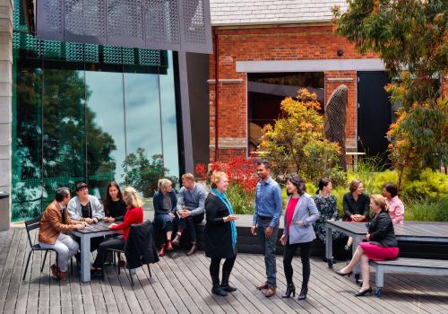 Adults sitting outside in small groups. 