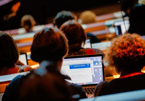 People sitting in a theatre looking at laptops. 