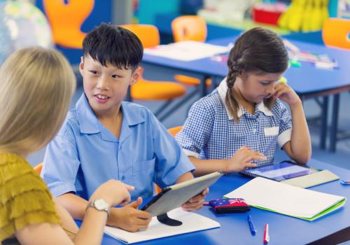 teacher with 2 primary students at desk