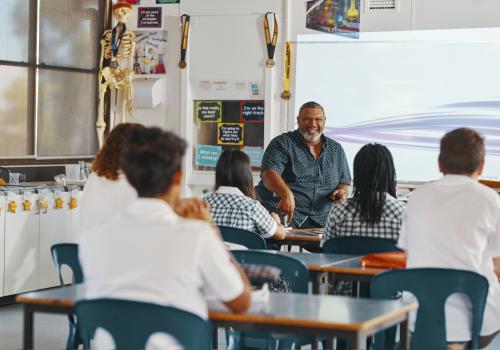 Teacher seated in front of class of seated students