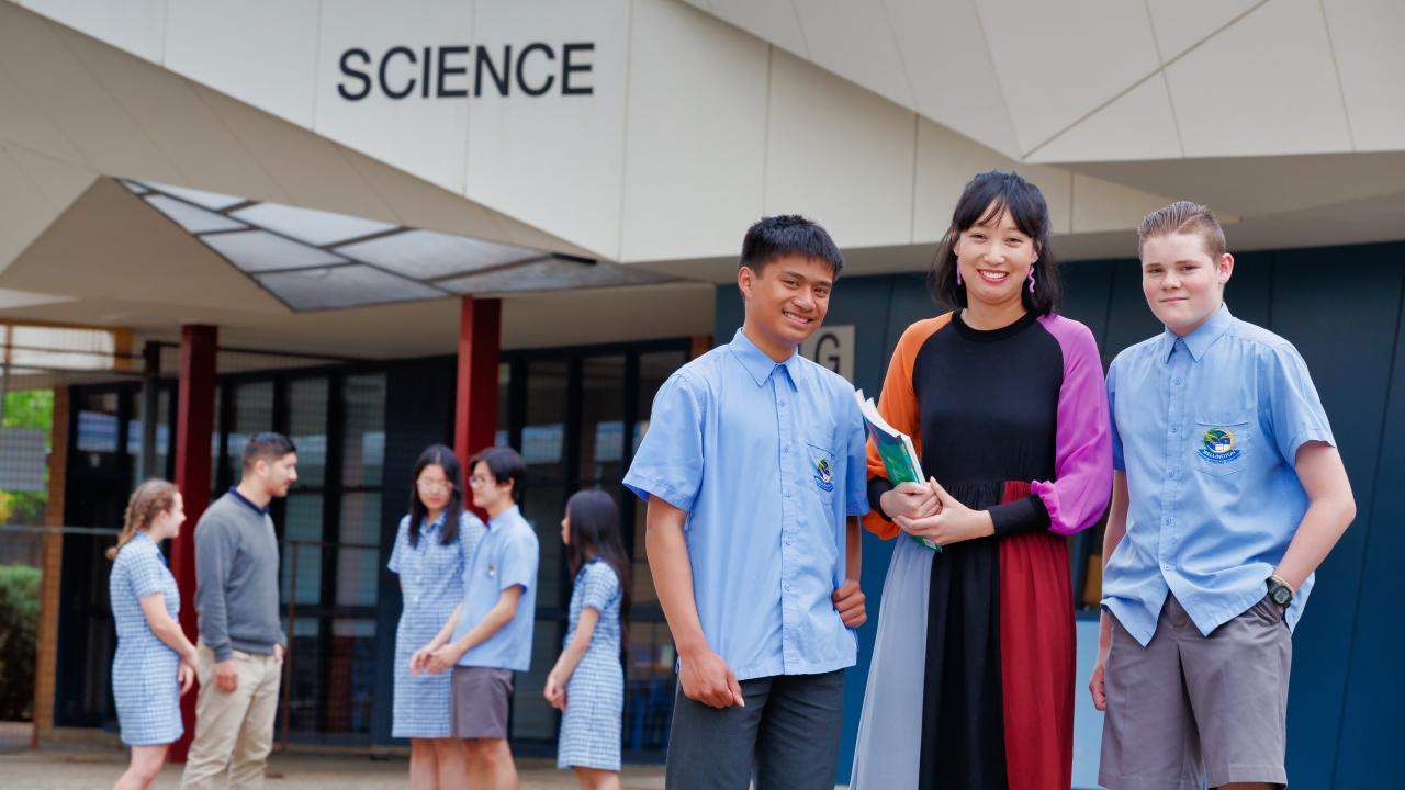 Female teacher with high school students in front of Science building