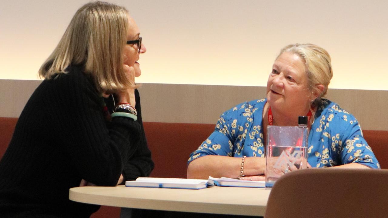 2 participants seated at table in discussion