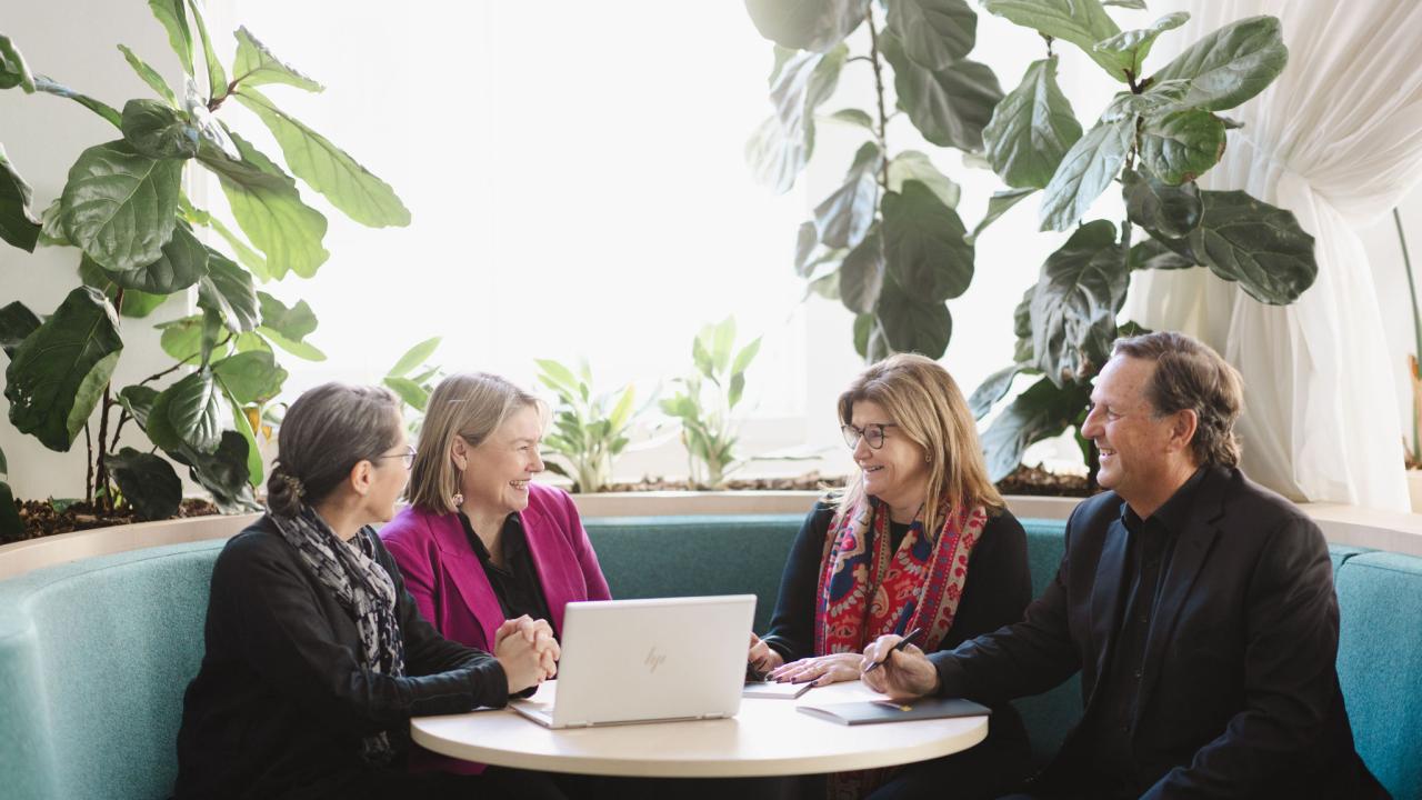 Groups of 4 participants seated at a table in discussion