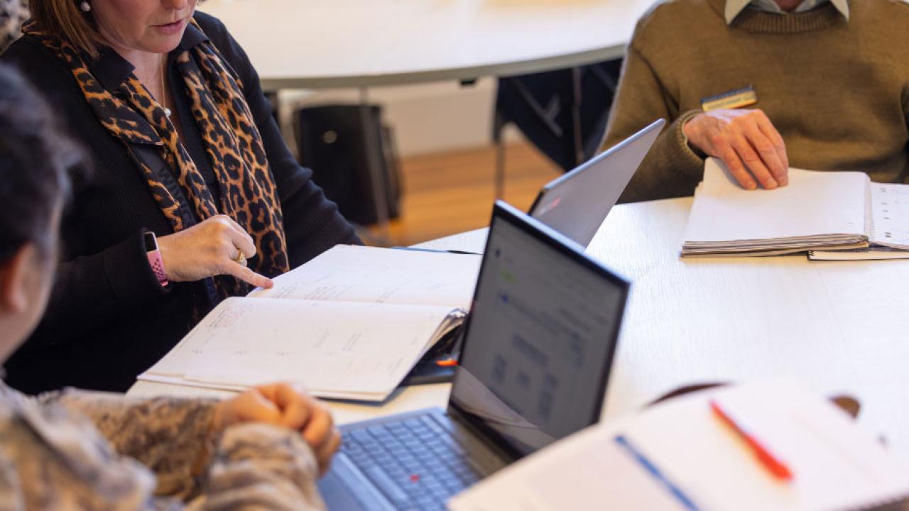 People working with computers and documents in a desk
