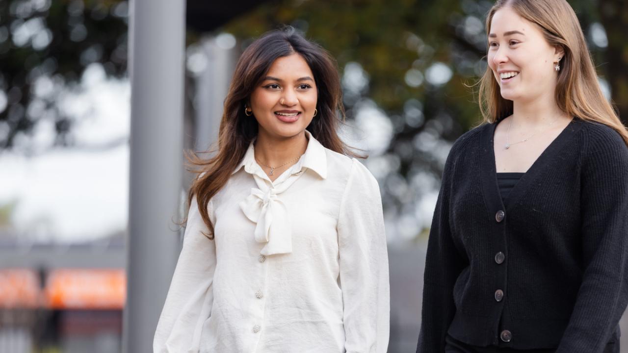 2 school teachers walking side by side outside on school grounds 