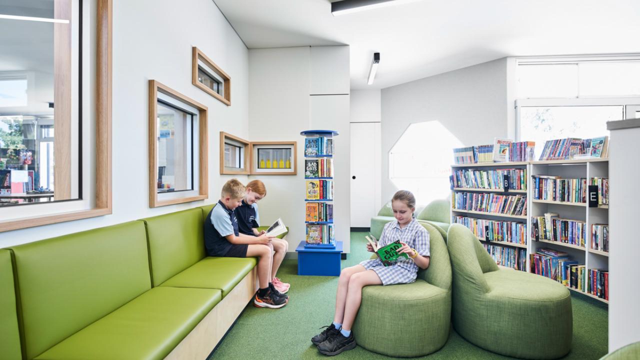 Primary students sitting and reading in the school library
