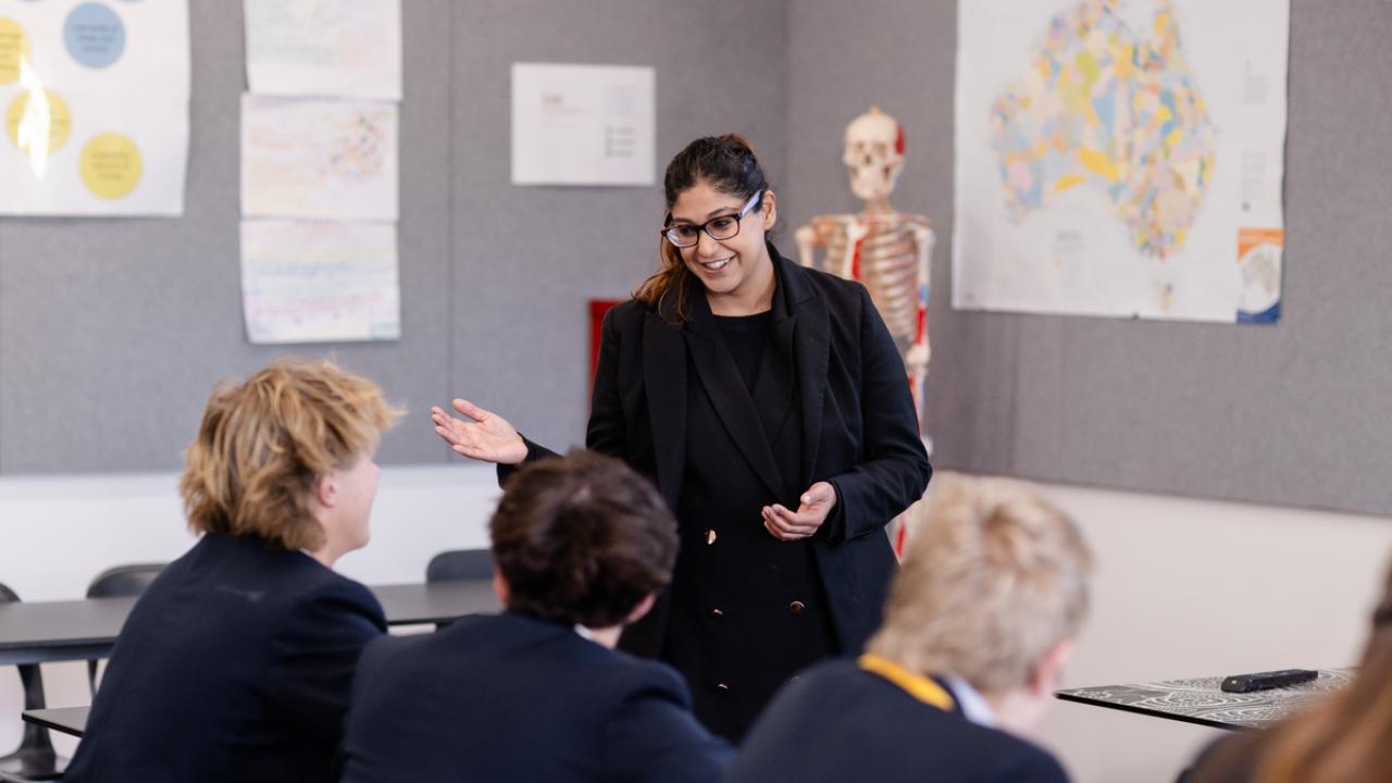 Teacher standing in front of the high school classroom speaking to students 