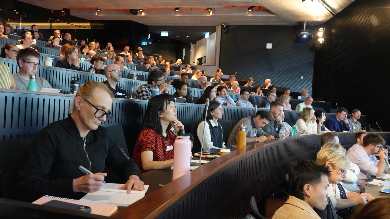 People sit in a lecture theatre listening to a speaker 
