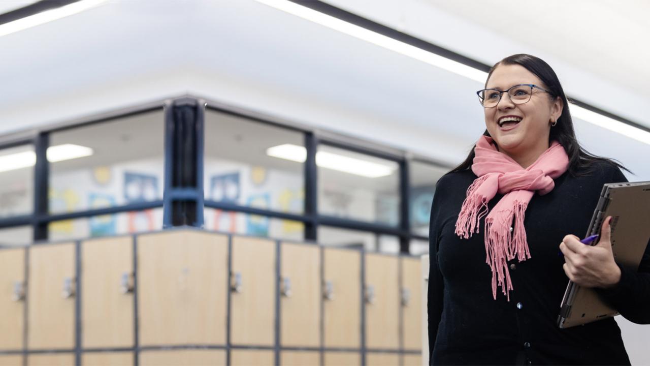 Leading teacher smiling proudly in school corridor