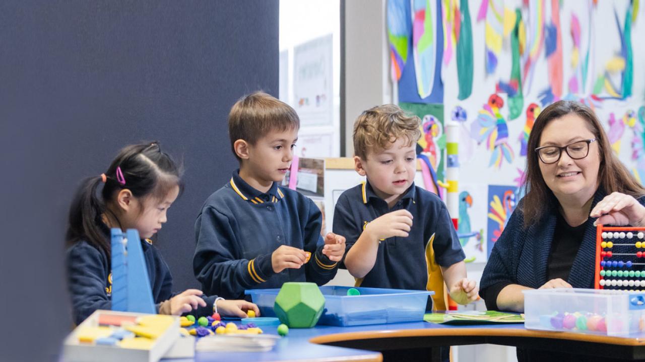maths teacher with primary school children counting beans and other activities in the maths corner table