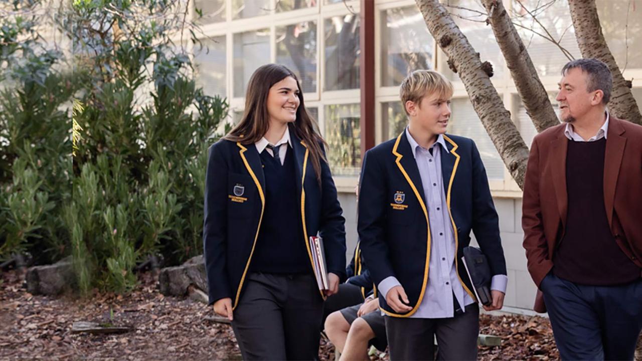 Principal of Sandringham leading through the school paved area with 2 students