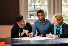Participants collaborating together at table with textas and white paper