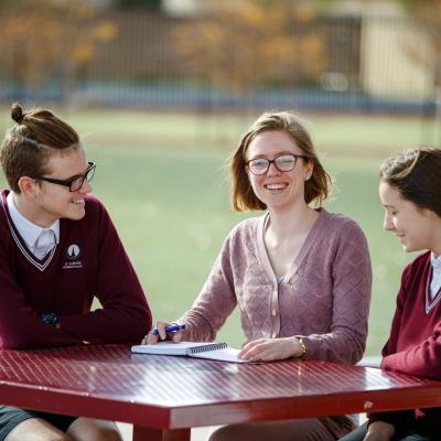 Female teacher sitting with high school students outdoors
