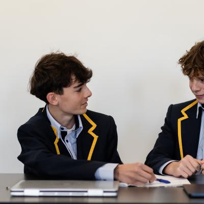 2 secondary students seated at table in discussion