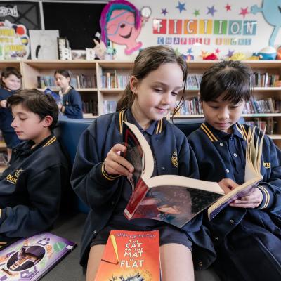 Primary school students are sitting and reading books in the library