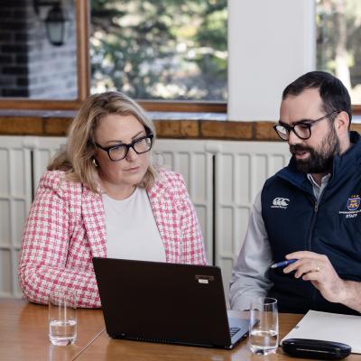 2 teachers seated at table looking at a laptop 