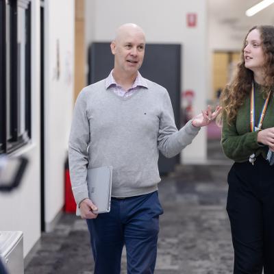 2 teachers with books in hand walking in school corridor
