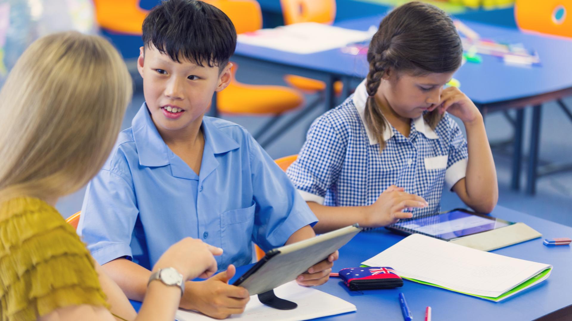 teacher with 2 primary students at desk